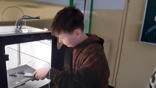 Chłopiec obsługuje drukarkę 3D
